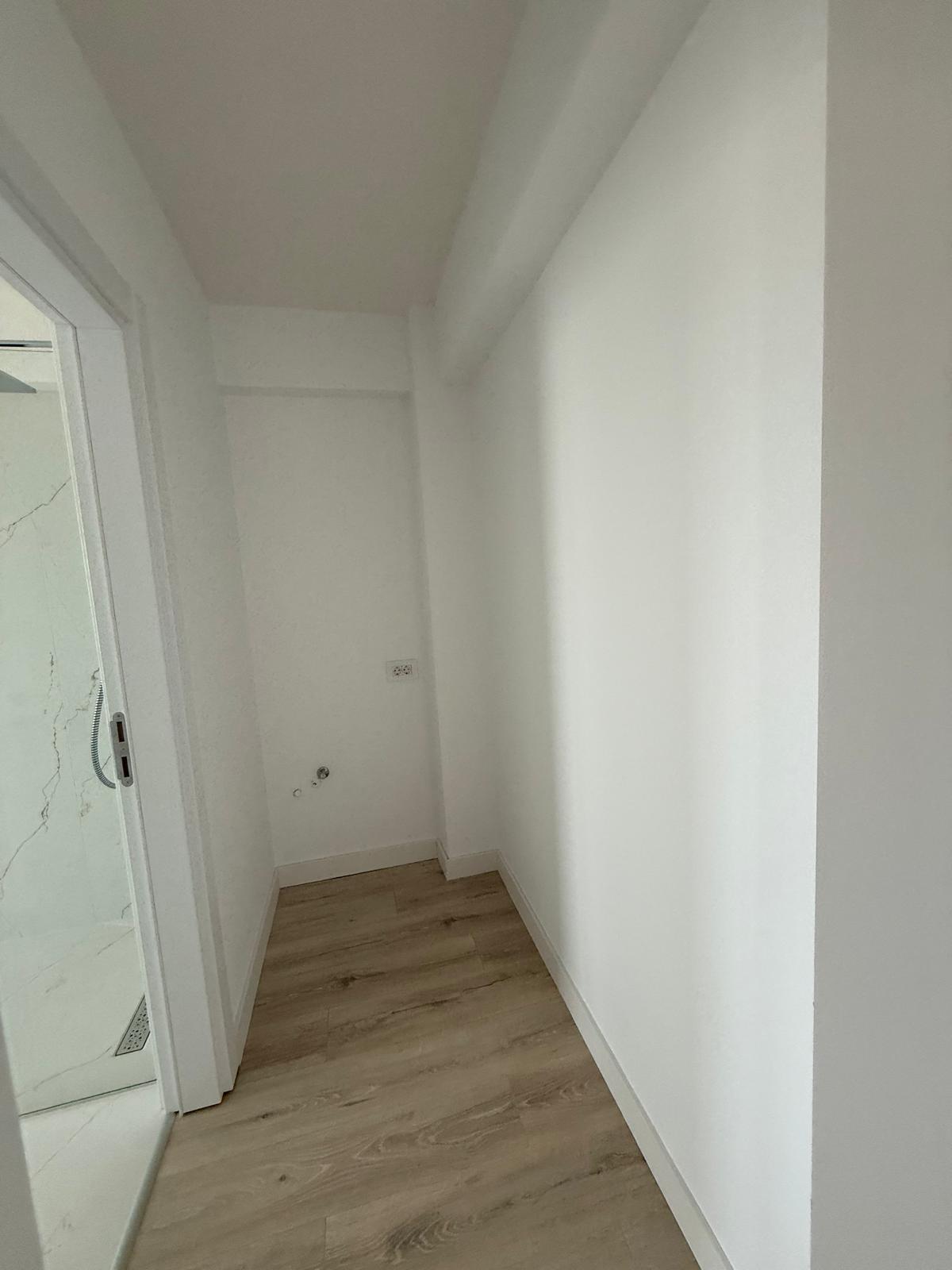 Hol tehnic cu intrare la baie cu faianță tip marmură și racorduri de apă pe perete