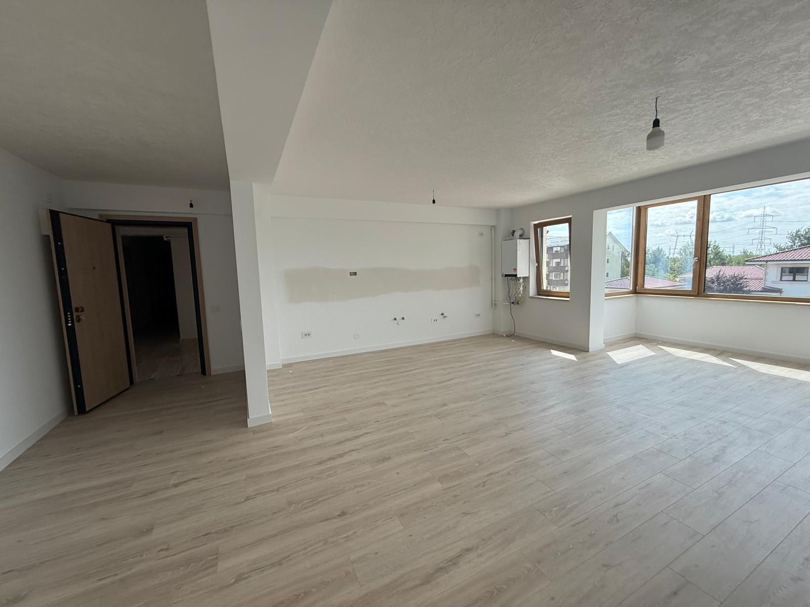 Zonă de zi open-space cu ferestre colț din lemn, centrală și podea parchet deschis