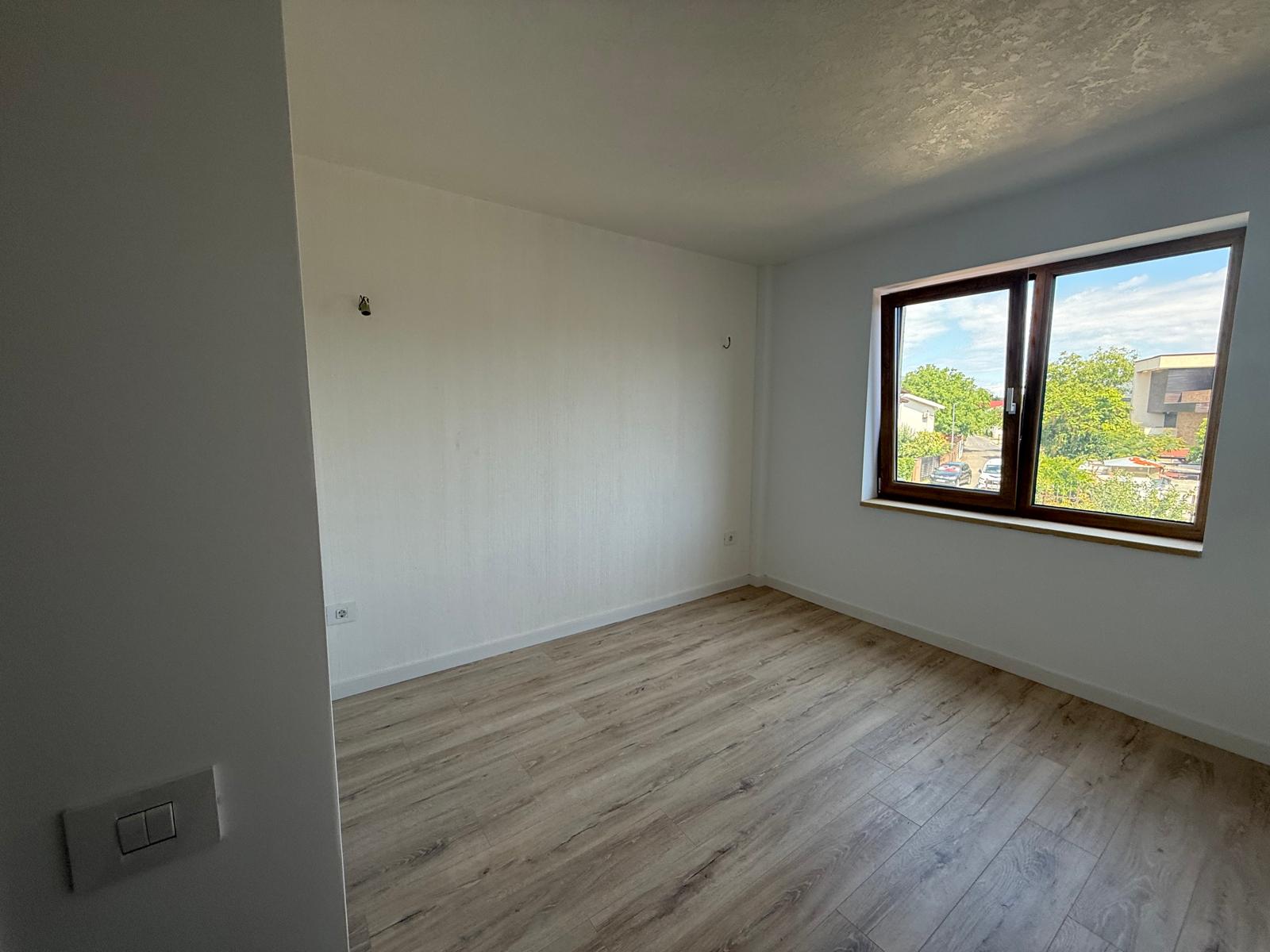Dormitor modern cu parchet deschis și fereastră dublă din lemn spre stradă