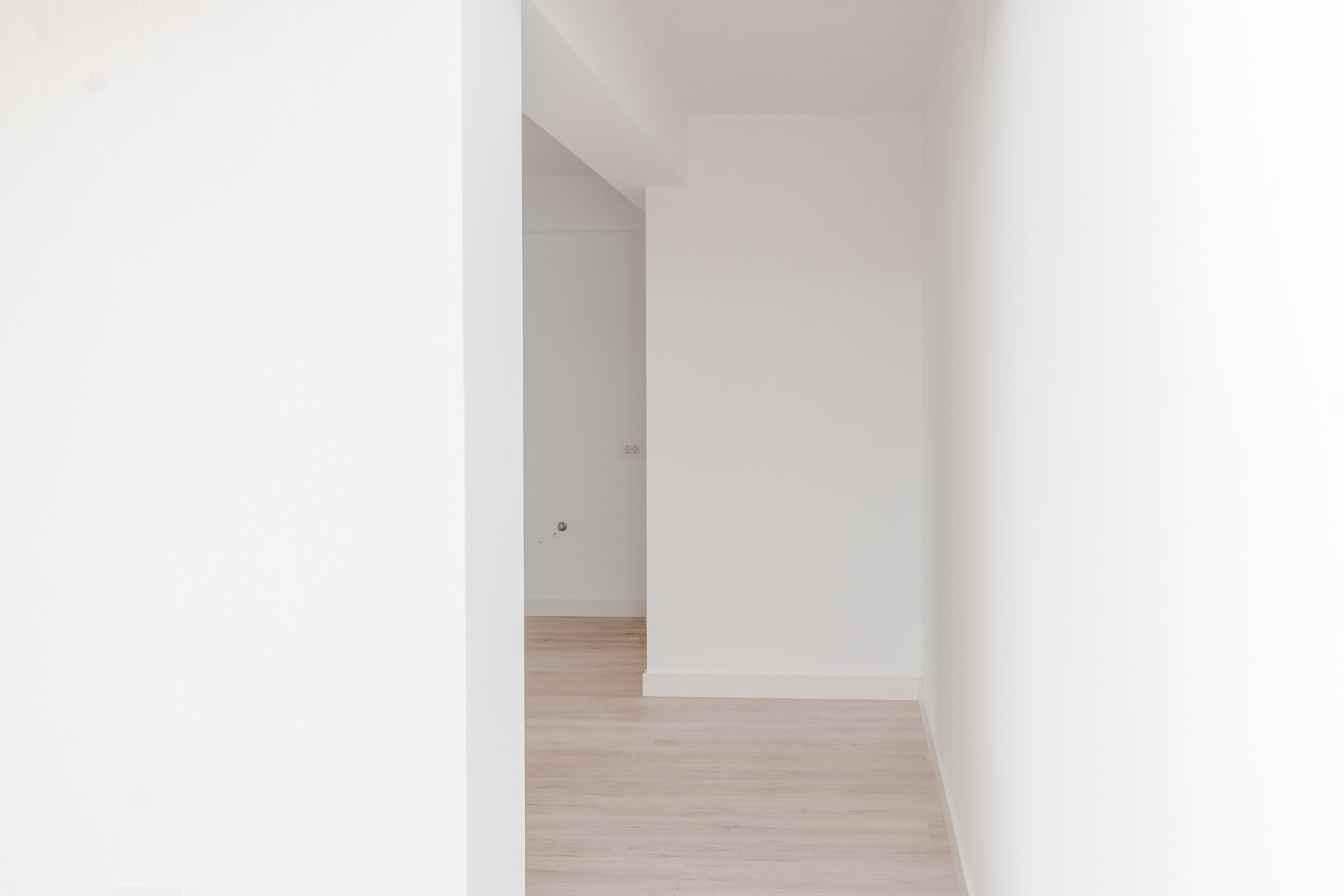 Hol luminos și minimalist cu pereți albi și parchet deschis