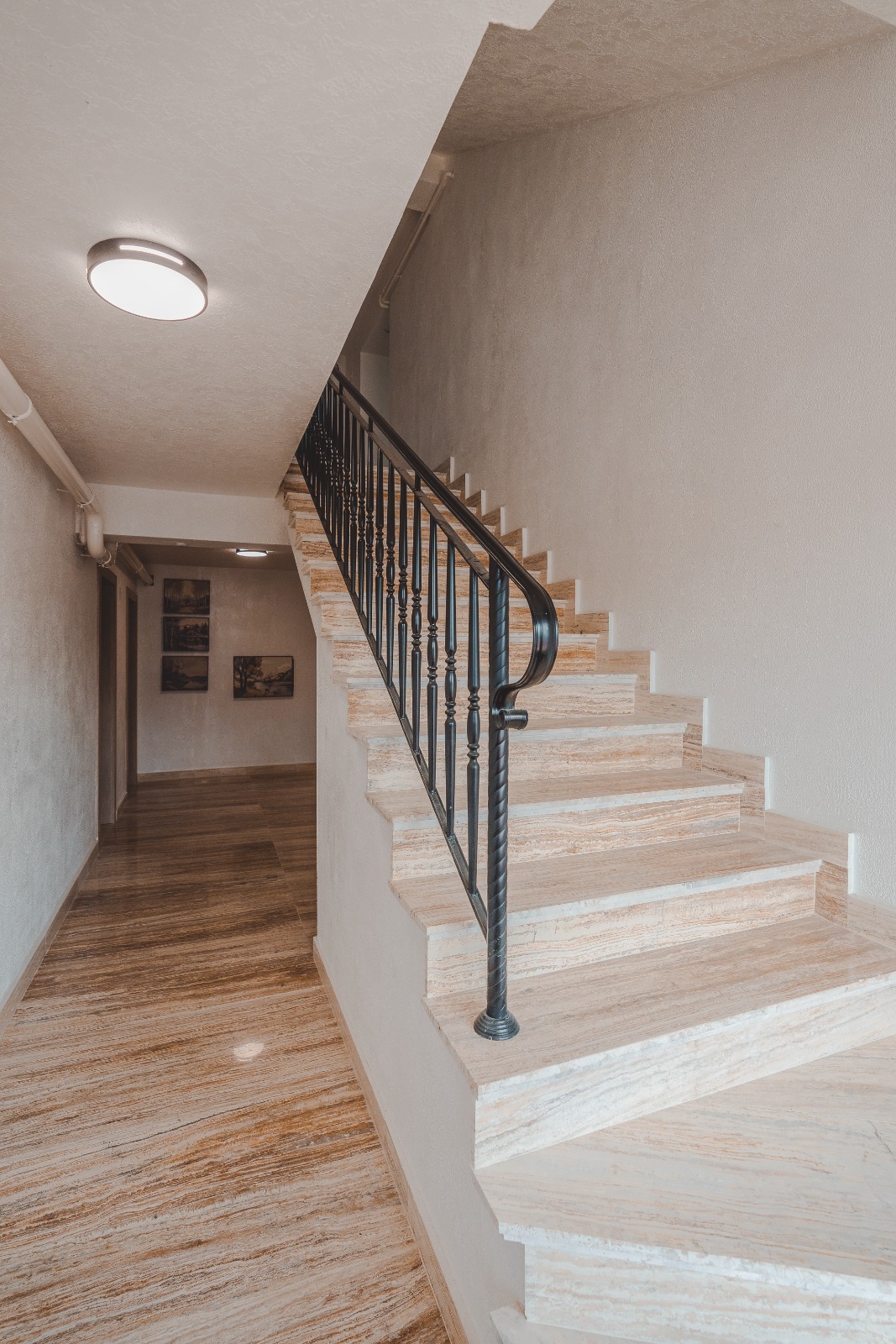 Casa scării — trepte placate cu travertin și balustradă metalică decorativă