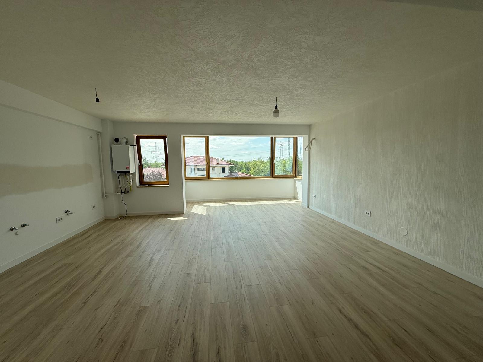 Living open-space cu ferestre panoramice din lemn, centrală termică și utilități expuse