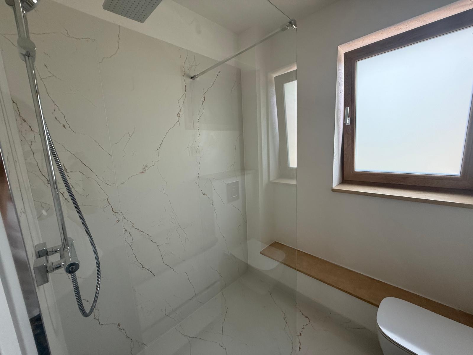 Baie cu duș walk-in din sticlă, geamuri matte și finisaje de marmură