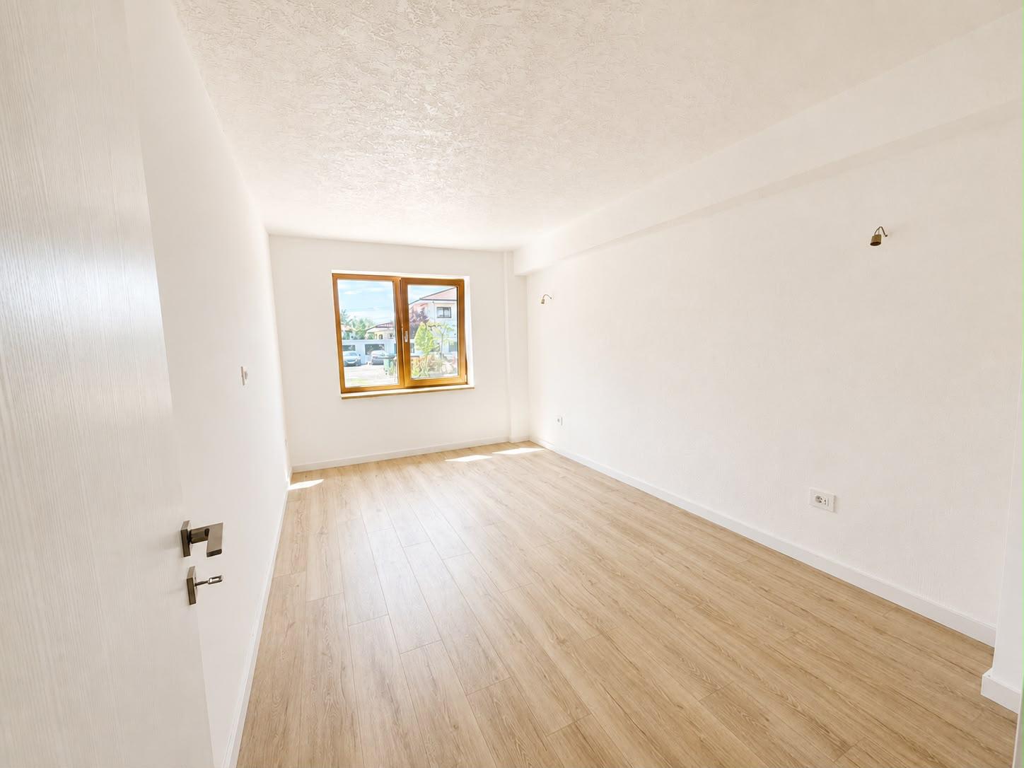 Cameră luminoasă cu fereastră mare și aplici de perete
