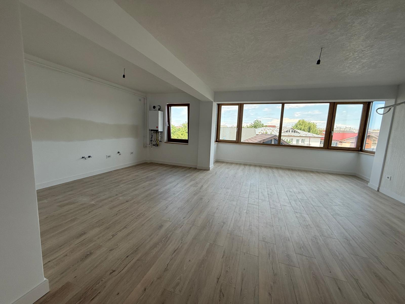 Living spațios cu parchet deschis, ferestre panoramice din lemn și grindă structurală aparentă