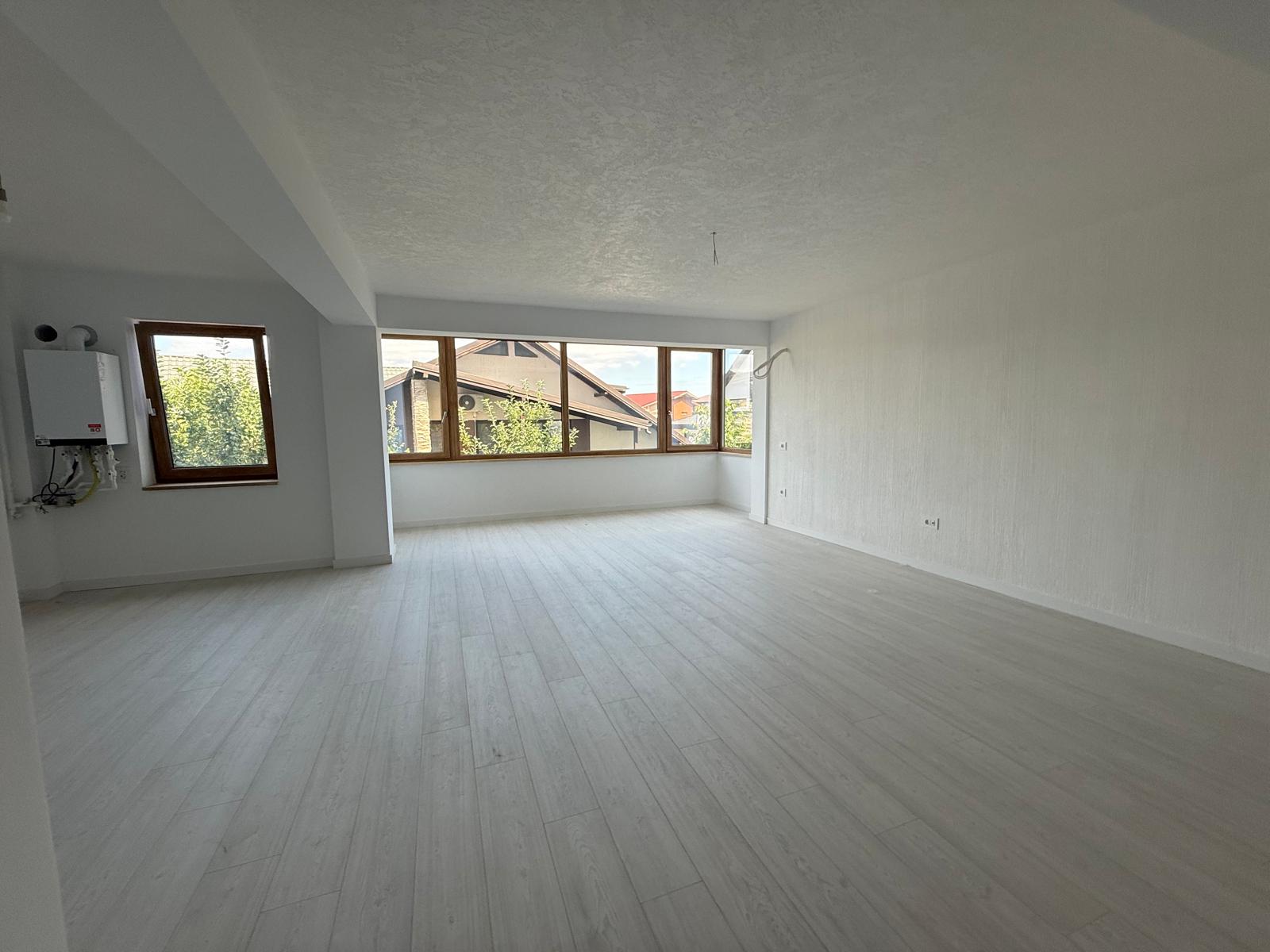 Living / zonă de zi open-space cu parchet deschis, centrală termică și ferestre mari din lemn