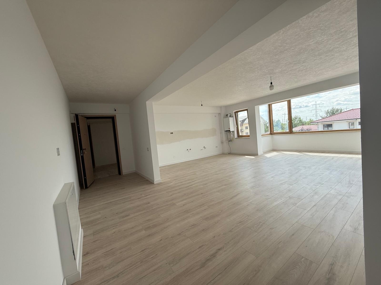 Living open-space cu ferestre panoramice colț, grindă aparentă și centrală termică
