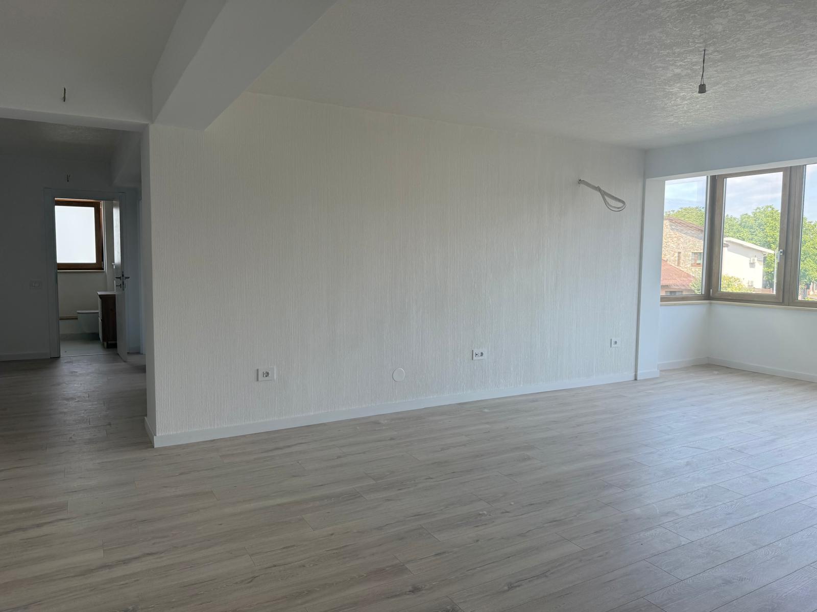 Living / zonă de zi open-space cu parchet deschis și fereastră mare din lemn