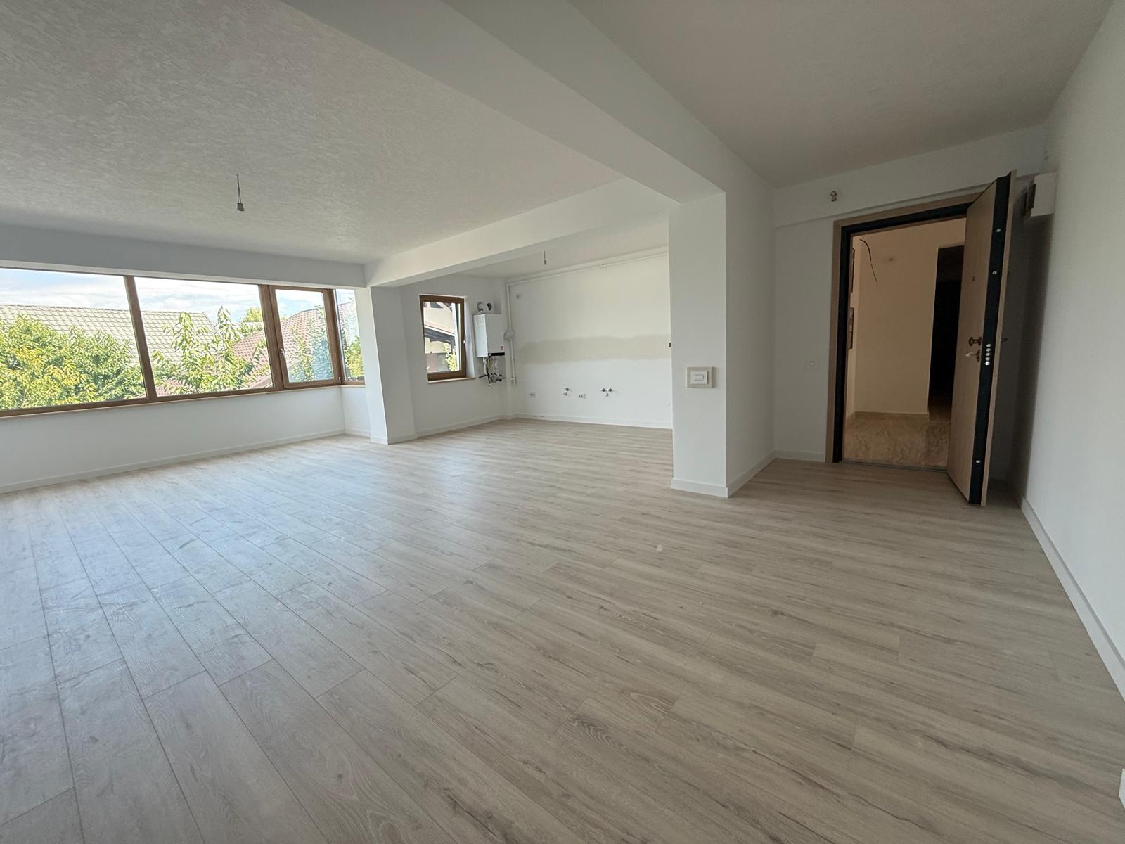 Living open-space cu zonă de bucătărie, centrală termică și ferestre mari